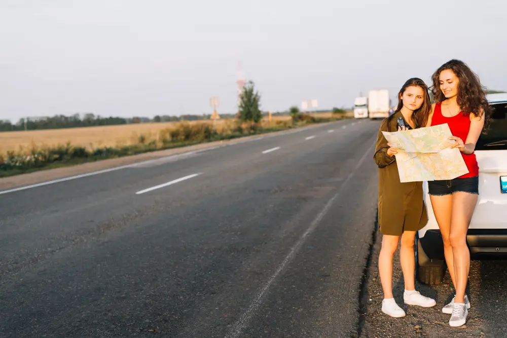 Women standing near white car with map