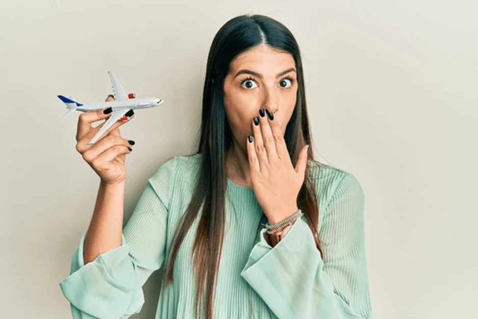 A woman holds a toy airplane in her right hand and looks up in surprise