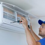 Specialist cleans and repairs the wall air conditioner