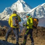 Two people on the mountain with essential equipment looking at each other