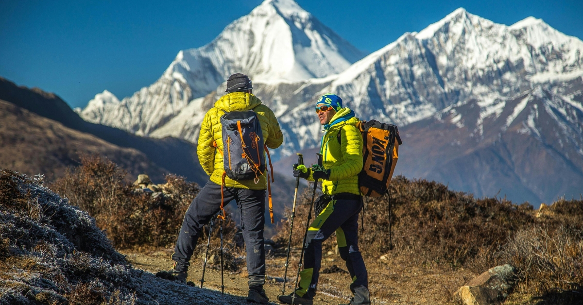 Two people on the mountain with essential equipment looking at each other
