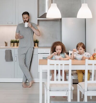 A Man Standing Beside His Kids while Using His Mobile Phone