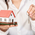 Female holding a toy model house and keys