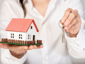 Female holding a toy model house and keys