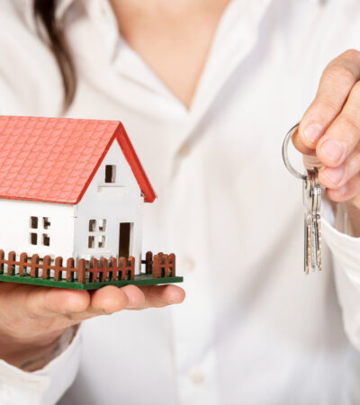 Female holding a toy model house and keys