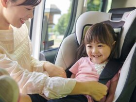 mother puts her baby in the front seat of a car