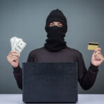 Thieves hold credit cards using a laptop